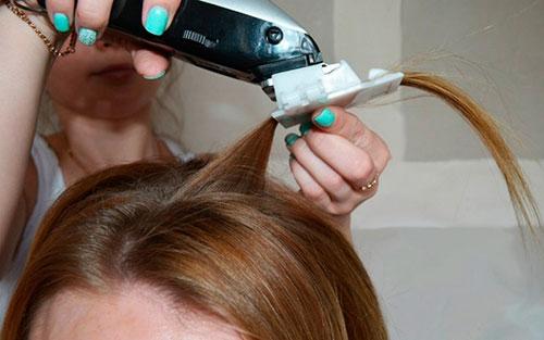 парикмахер делает полировку волос насадкой на машинку для стрижки
