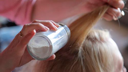 девушке наносят на волосы сухой шампунь сделанный в домашних условиях