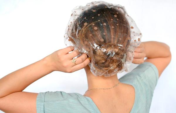 девушка с полиэтиленовой шапочкой на голове после нанесения маски