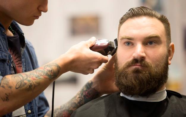 парикмахер делает мужчине стрижку Топ Кнот